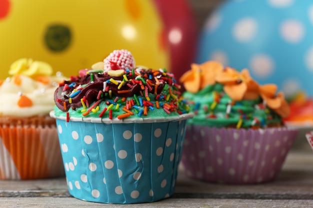 Delicious birthday cupcakes on table on bright background