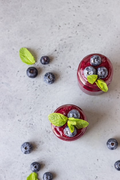 Delicious blueberry smoothie with fresh berries and mint in glass jars. Summer healthy drink.