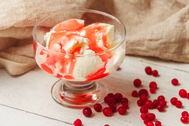 Delicious bowl of vanila ice cream with strawberry topping and cranberries