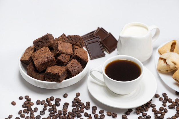 Delicious breakfast aromatic coffee in a cup milk jug chocolate and cake cubes