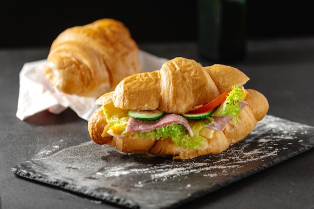 Delicious breakfast big croissant sandwich with sausage cheese and tomato