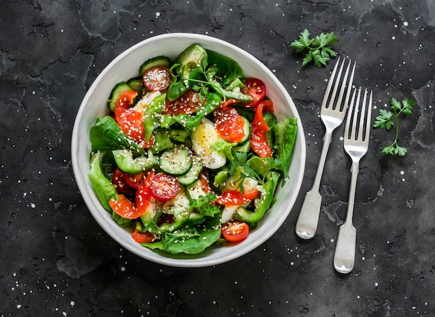 Delicious breakfast snack tapas salad with salted salmon egg vegetables lettuce on a dark background top view