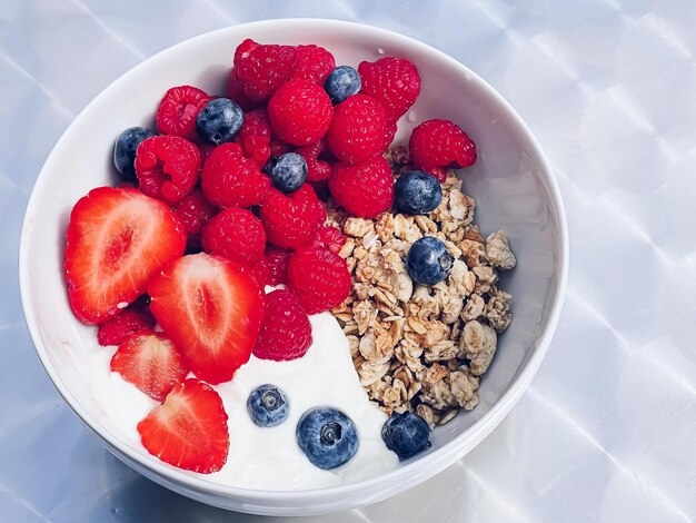 Delicious breakfast with cereal yogurt strawberries raspberries and bluberries in the garden outdoors healthy food and diet