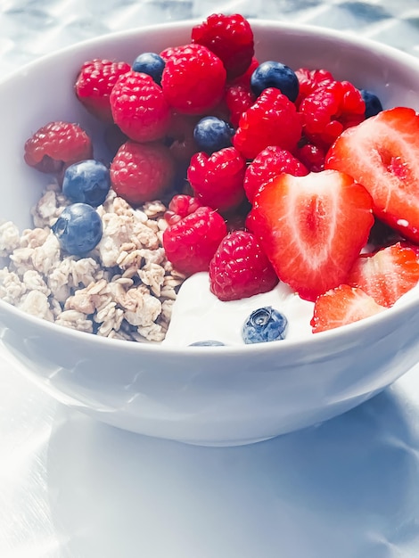 Delicious breakfast with cereal yogurt strawberries raspberries and bluberries in the garden outdoors healthy food and diet