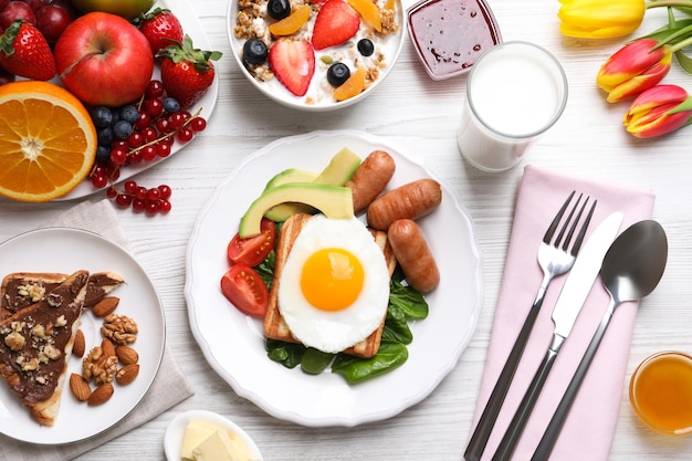 Delicious breakfast with fried egg served on white wooden table flat lay