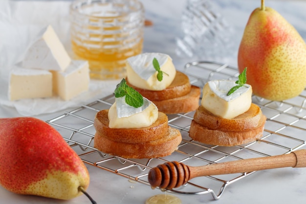 Delicious bruschetta with caramelized pear camembert or brie cheese honey and mint Fruit dessert Bread toast crostini Healthy breakfast for gourmets Selective focus copy space