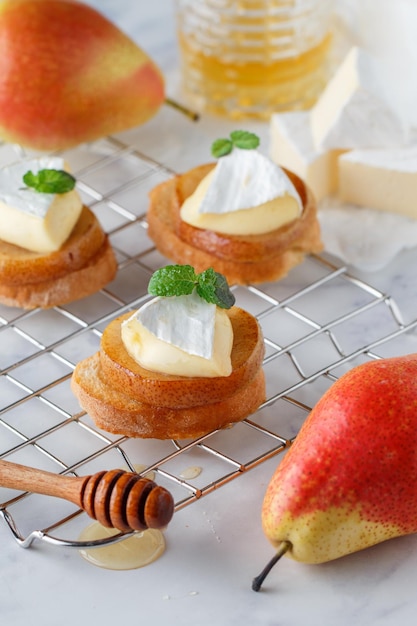 Delicious bruschetta with caramelized pear camembert or brie cheese honey and mint Fruit dessert Bread toast crostini Healthy breakfast for gourmets Selective focus copy space