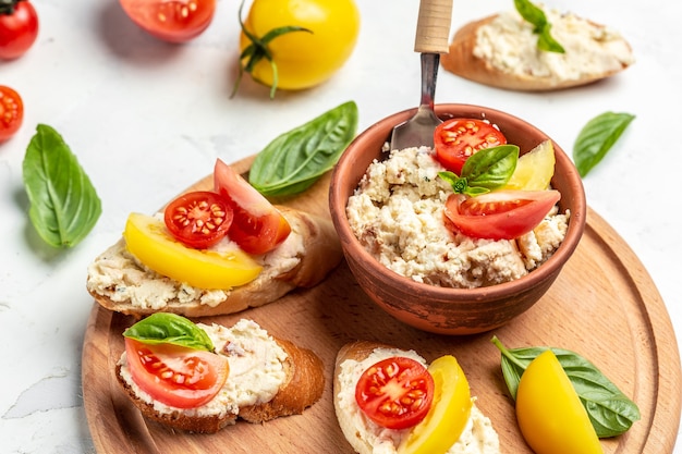 Delicious bruschetta with tomatoes, cream cheese and basil leaves on wooden board, Food recipe background. Close up