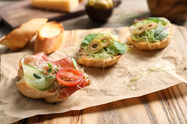 Delicious bruschettas with prosciutto served on wooden board