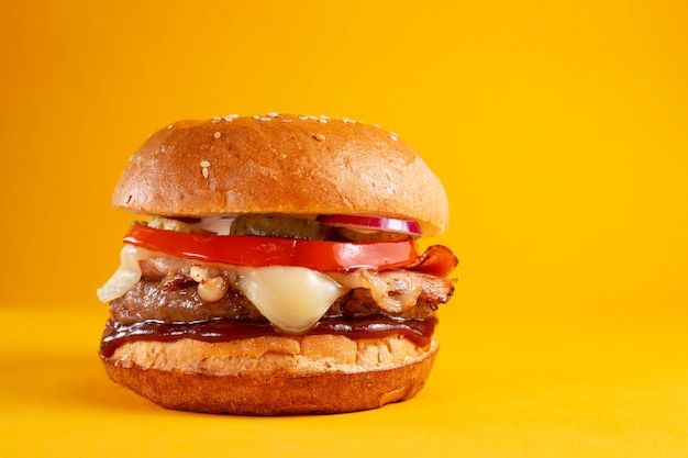 Delicious burger isolated on yellow background. Tasty fresh unhealthy hamburgers with cheese