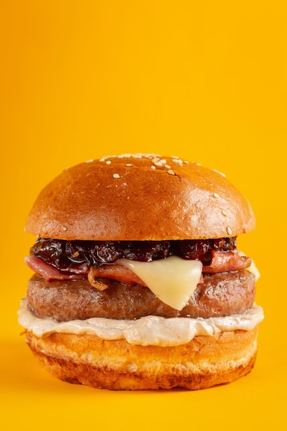 Delicious burger on a yellow background. Tasty fresh unhealthy burgers with cheese and two patties. Fast food, unhealthy food concept.