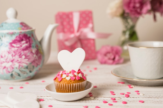 Delicious cake near teapot, present and cup