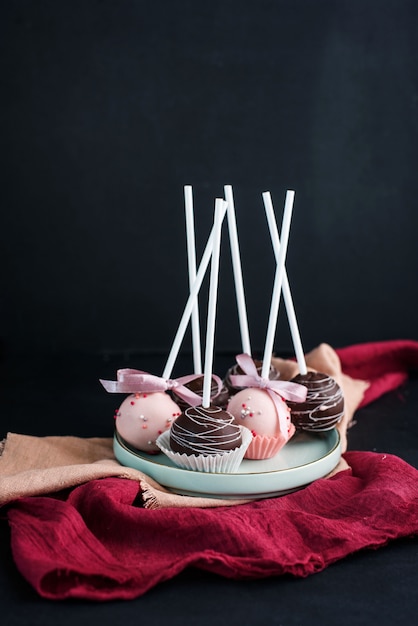 Delicious cake pops on a plate in a dark way.