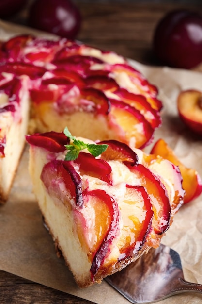 Delicious cake with plums on wooden table closeup