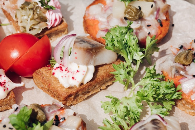 Delicious canapes with herring.Macro of delicious canape or sandwiches with fresh herring, black sesame, cream cheese on crispy bread.