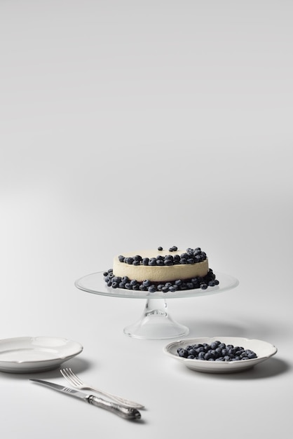 Delicious cheesecake with blueberries on glass stand with plates and cutlery