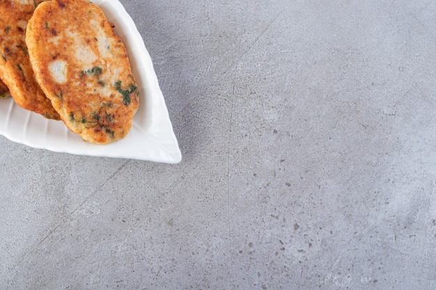 Delicious chicken cutlets with vegetables and salt on stone table.