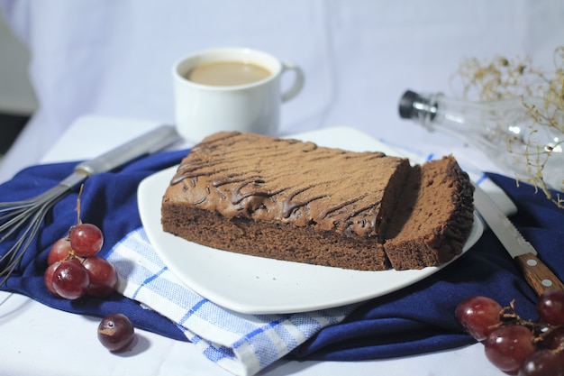 Delicious chocolate brownies on a white plate with glass of coffee grape and knife around