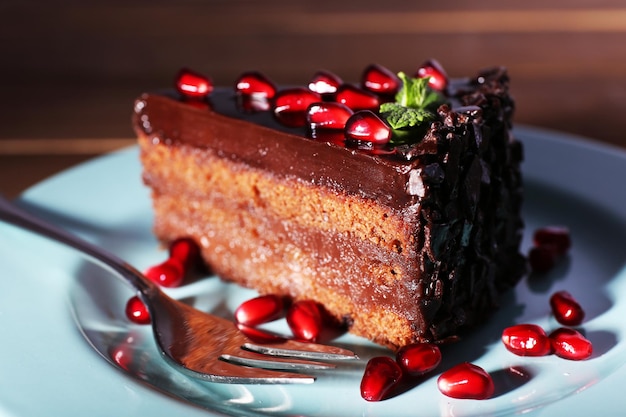 Delicious chocolate cake decorated with pomegranate seeds on plate on table