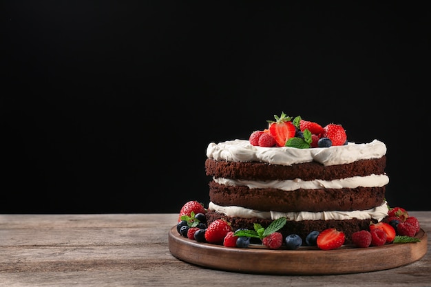 Delicious chocolate cake with berries on table