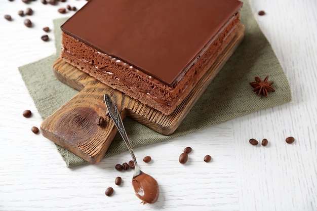 Delicious chocolate cake on wooden cutting board closeup