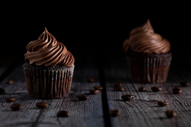 Delicious chocolate and coffee cupcakes under softlight on wooden table