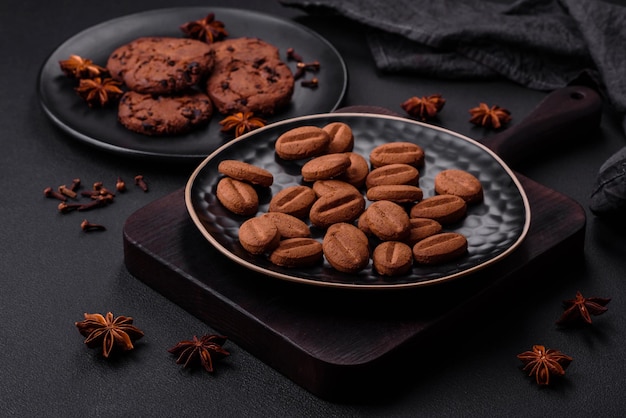 Delicious chocolate cookies with nuts on a black ceramic plate on a dark concrete background