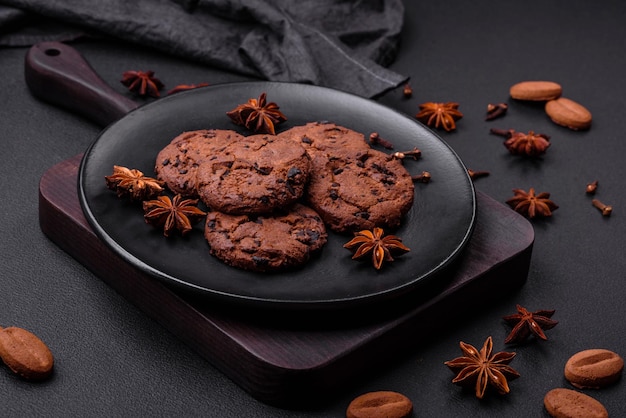 Delicious chocolate cookies with nuts on a black ceramic plate on a dark concrete background