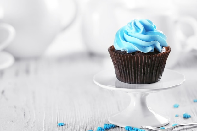 Delicious chocolate cupcake with blue cream on served table close up