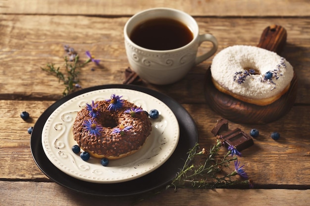 Delicious chocolate doughnuts and cup of coffee on wooden table closeup