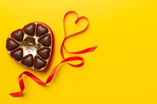 Delicious chocolate pralines in red box for Valentine's Day. Heart shaped box of chocolates top view with copy space.