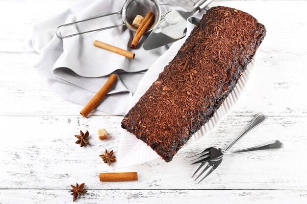 Delicious chocolate roll with spices on wooden table closeup