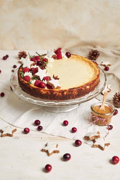 Delicious Christmas cheesecake with cranberries and cookies stars on a white table