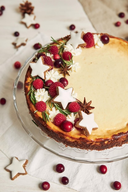 Delicious Christmas cheesecake with cranberries and cookies stars on a white table