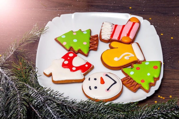 Delicious Christmas cookies in a plate near a Christmas tree branch