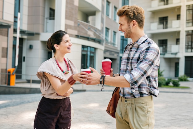 Delicious coffee. Happy young woman taking a drink while looking at her boyfriend