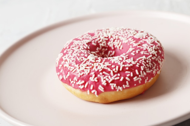 Delicious colorful donuts with sprinkles on stylish plate on white table with confetti, flat lay. Party concept. No diet. Candy bar at wedding reception. Purple and pink donuts