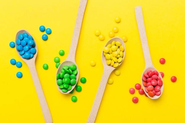 Delicious colorful sweet candies on spoon on colored background Confectionery decor top view with copy space