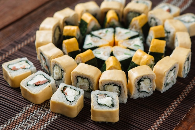 Delicious colorful tasty set of sushi rolls served on straw mat, closeup. Japanese luxury restaurant menu photo, traditional seafood.