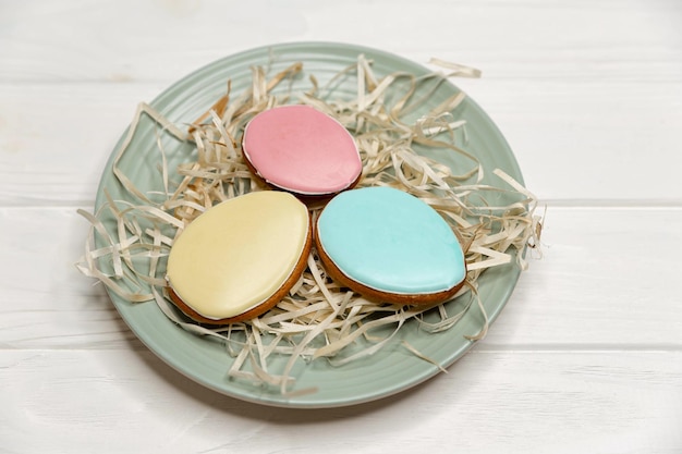 Delicious cookies with colorful glaze on a plate on white wood