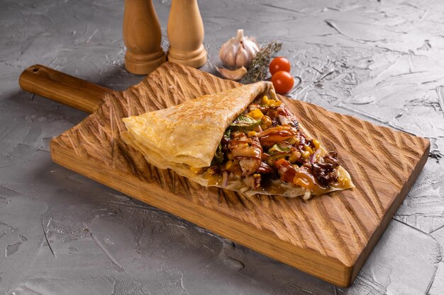 Delicious crepes pancake with vegetables chicken mushrooms on wooden cutting board top view homemade