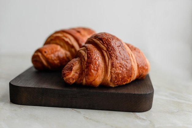 Delicious crispy croissant with chocolate with a cup of invigorating coffee on a light concrete background Delicious nutritious breakfast