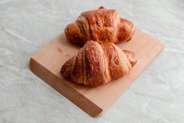 Delicious crispy croissant with chocolate with a cup of invigorating coffee on a light concrete background Delicious nutritious breakfast