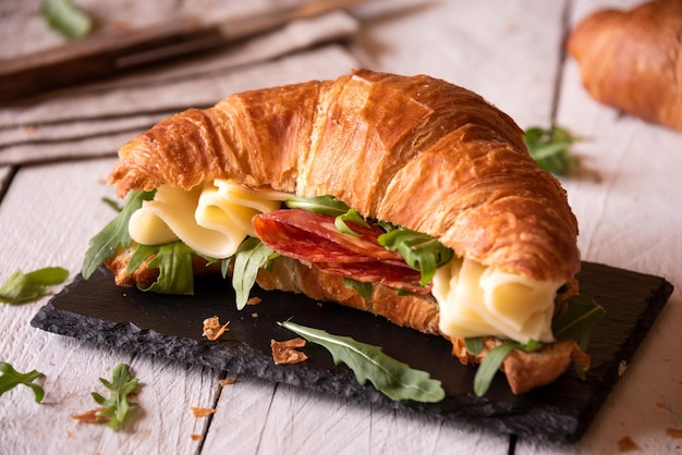 Delicious croissant sandwich with cheese and arugula