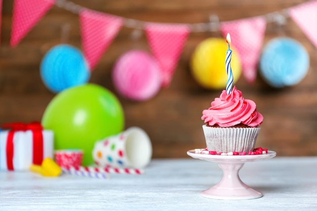 Delicious cupcake with lighted candle against festive background