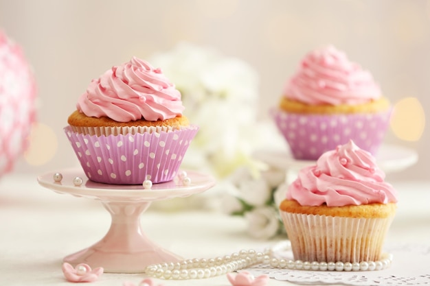 Delicious cupcakes on table on light background