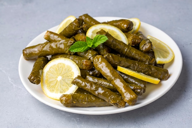 Delicious dolma (sarma) stuffed grape leaves rice, white yogurt sauce. Lebanese dolma sarma on plate. Lebanon turkish greek middle eastern cuisine. (Turkish name; Yaprak sarma)