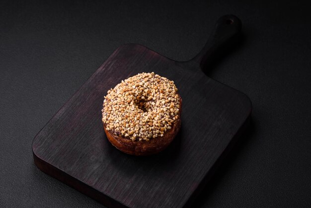 Delicious donut with cream filling and nuts on a dark concrete background