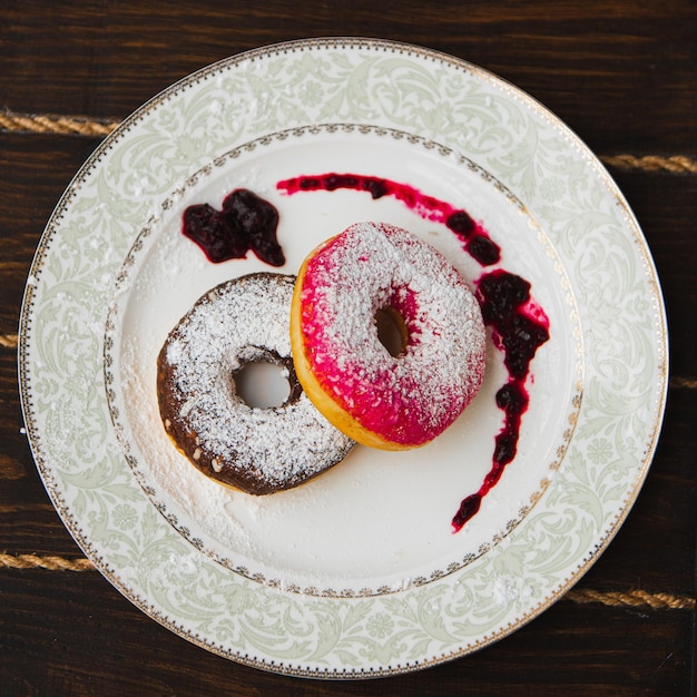 Delicious donuts with icing on plate on dark wooden background. soft focus