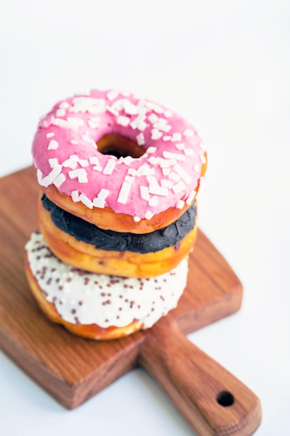 Delicious donuts on wooden board placed on wooden cutting board on white background